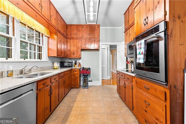 kitchen with sink, light tile patterned flooring, ornamental molding, and appliances with stainless steel finishes