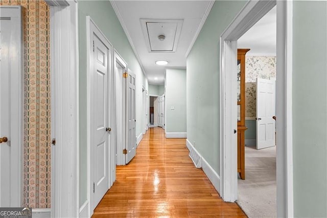 hallway with crown molding and light hardwood / wood-style flooring