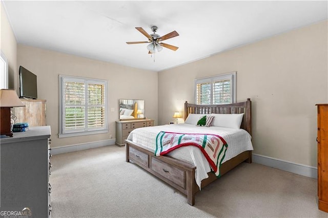 bedroom with multiple windows, ceiling fan, and light carpet