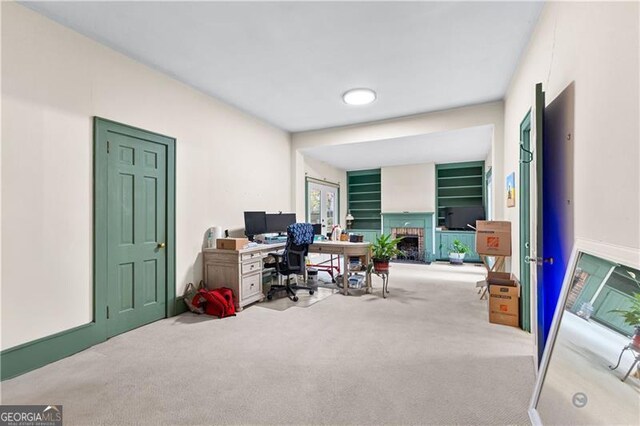 carpeted home office featuring a brick fireplace