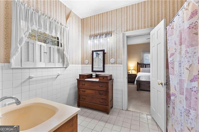 bathroom with tile patterned floors, curtained shower, vanity, and tile walls