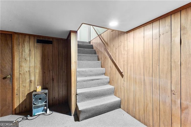 staircase with carpet floors and wooden walls