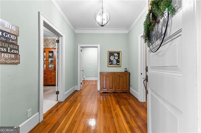 hallway featuring hardwood / wood-style flooring, crown molding, and an inviting chandelier