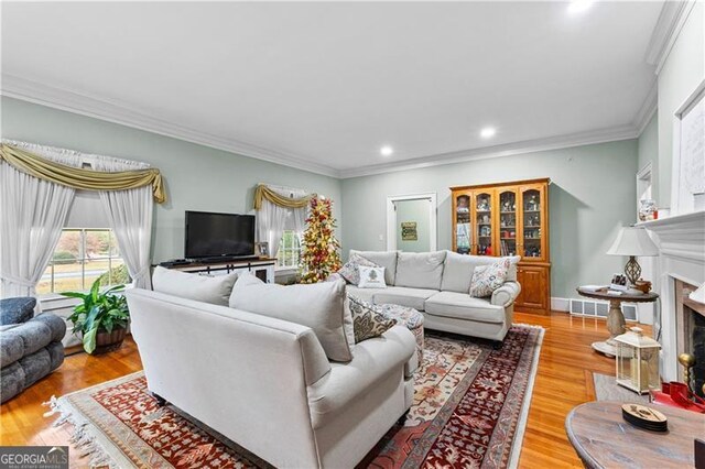 living room featuring a fireplace, ornamental molding, and light hardwood / wood-style flooring