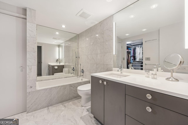 full bathroom with tiled shower / bath, vanity, toilet, and tile walls