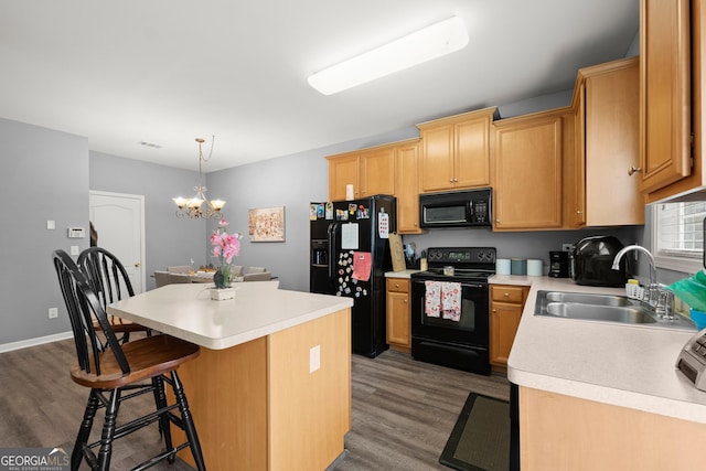 kitchen with a center island, black appliances, sink, dark hardwood / wood-style floors, and decorative light fixtures