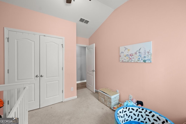 bedroom with ceiling fan, light colored carpet, vaulted ceiling, a closet, and a crib