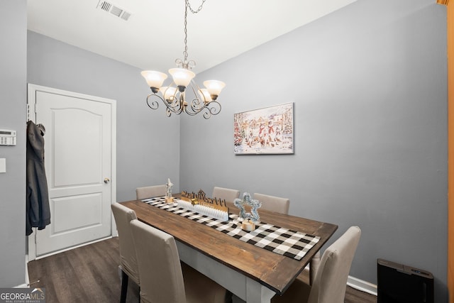 dining space featuring dark hardwood / wood-style flooring and an inviting chandelier