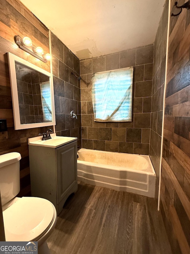 full bathroom featuring hardwood / wood-style floors, vanity, tiled shower / bath combo, and toilet