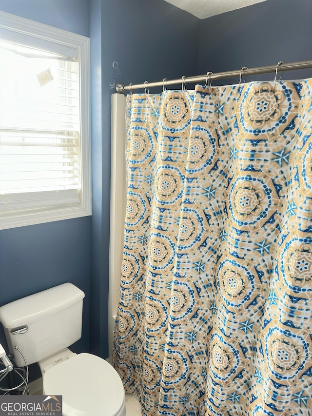 bathroom with curtained shower, tile patterned floors, and toilet