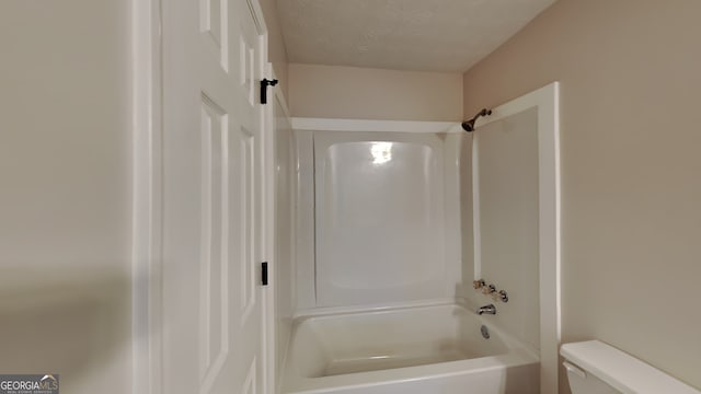 bathroom featuring a textured ceiling, bathtub / shower combination, and toilet