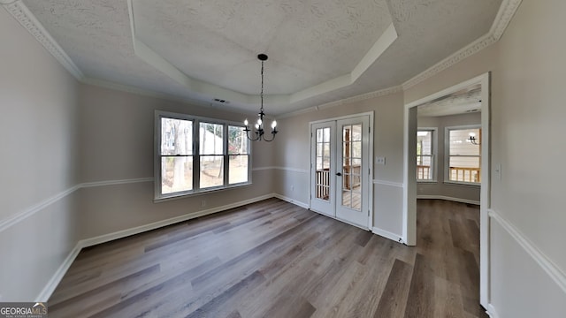 unfurnished dining area featuring french doors, hardwood / wood-style flooring, ornamental molding, a textured ceiling, and a tray ceiling