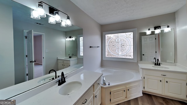 bathroom with vanity, wood-type flooring, a textured ceiling, and a bathing tub