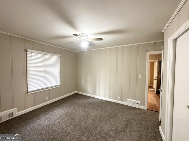 empty room with ceiling fan, dark carpet, and ornamental molding