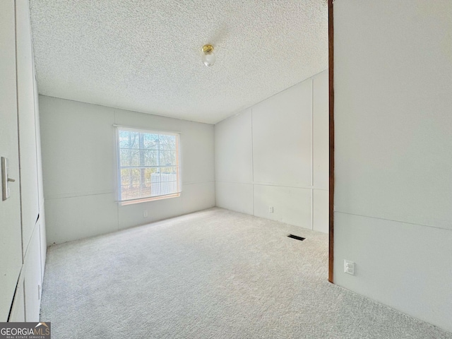 spare room with carpet floors, visible vents, and a textured ceiling