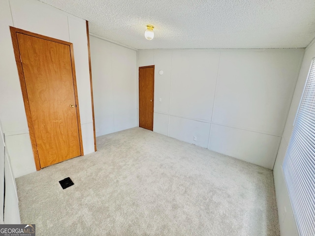 spare room featuring carpet flooring and a textured ceiling