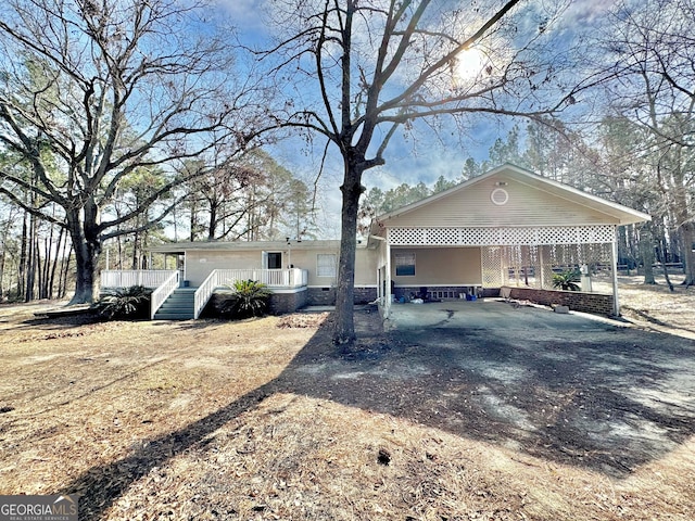 view of front of property with a carport, a porch, and dirt driveway