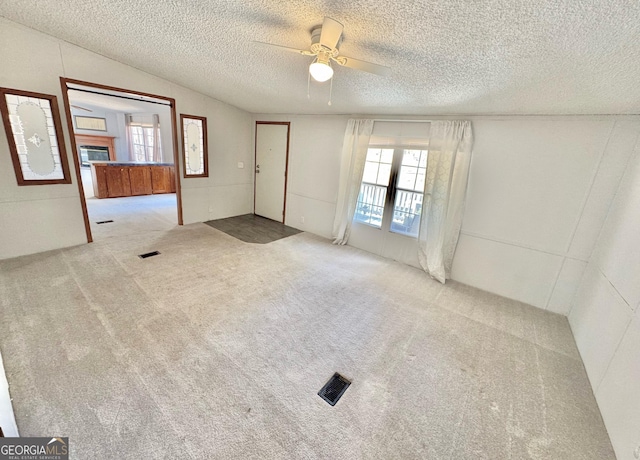 carpeted spare room with lofted ceiling, a ceiling fan, a textured ceiling, and french doors