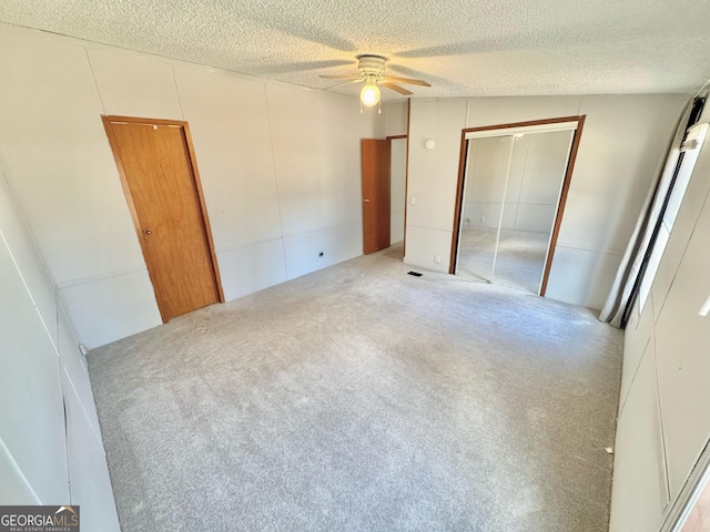 unfurnished bedroom with carpet, a closet, a ceiling fan, and a textured ceiling