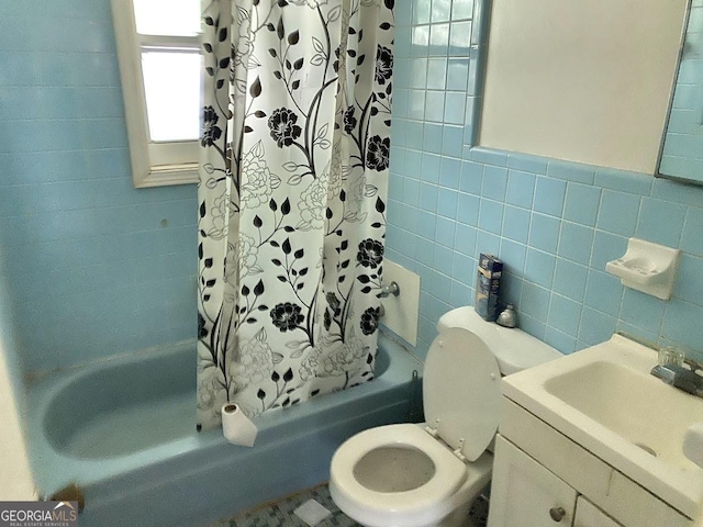 full bathroom with vanity, toilet, tile walls, and shower / bath combo with shower curtain