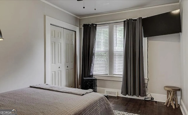 bedroom with multiple windows, a closet, dark hardwood / wood-style flooring, and ornamental molding