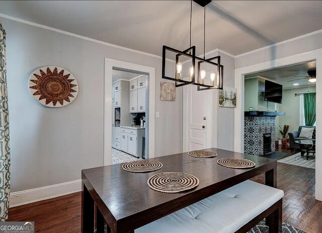 dining area featuring ornamental molding, ceiling fan with notable chandelier, and dark wood-type flooring