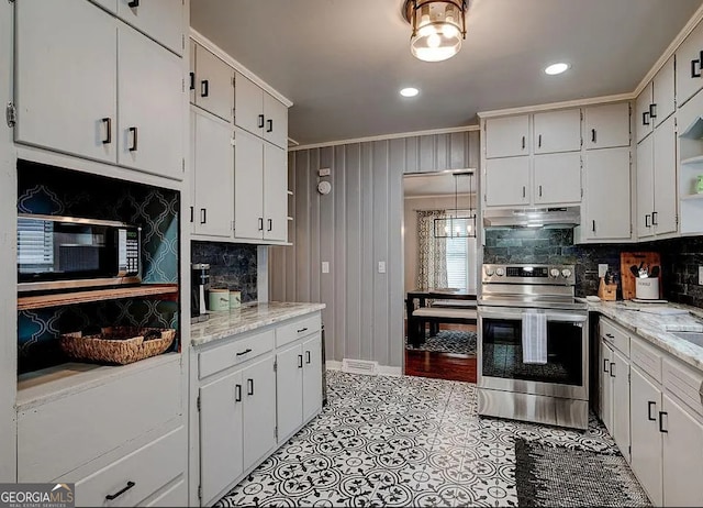 kitchen with light stone countertops, white cabinetry, stainless steel appliances, and tasteful backsplash