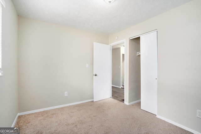 unfurnished bedroom featuring light carpet, a textured ceiling, and a closet