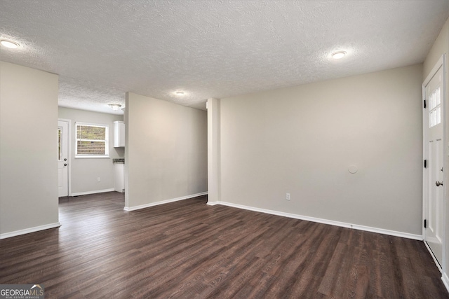 unfurnished room with a textured ceiling and dark hardwood / wood-style flooring