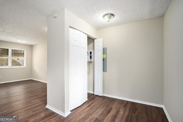 hall featuring a textured ceiling, dark hardwood / wood-style flooring, and electric panel