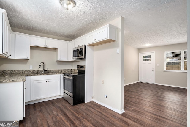 kitchen featuring appliances with stainless steel finishes, dark hardwood / wood-style flooring, sink, dark stone countertops, and white cabinets