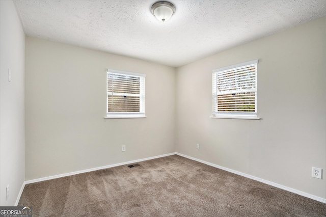 unfurnished room with a textured ceiling and light colored carpet