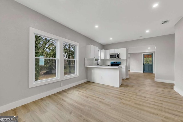 kitchen with white cabinetry, sink, black range with electric cooktop, light hardwood / wood-style flooring, and kitchen peninsula