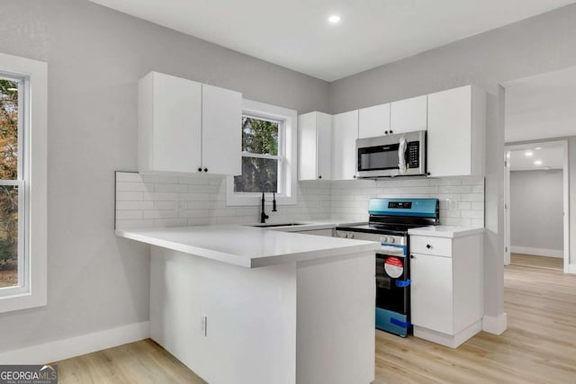 kitchen featuring white cabinets, stainless steel appliances, plenty of natural light, and sink