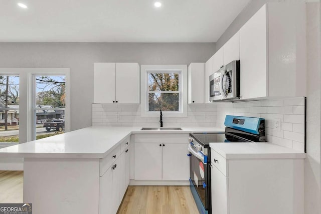 kitchen featuring white cabinets, sink, a wealth of natural light, appliances with stainless steel finishes, and kitchen peninsula