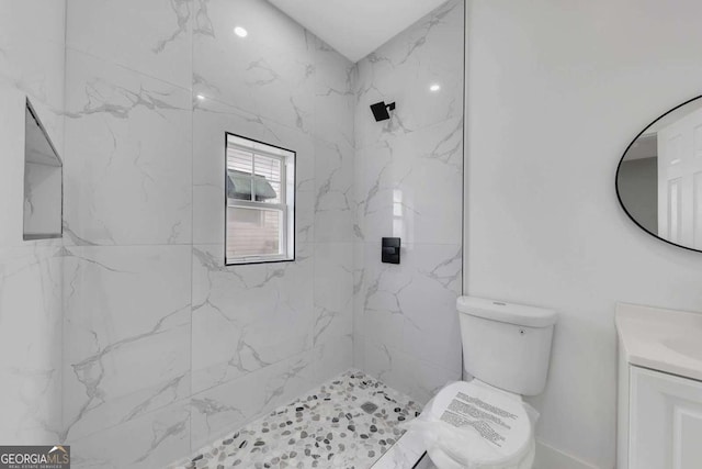 bathroom with vanity, toilet, and tiled shower