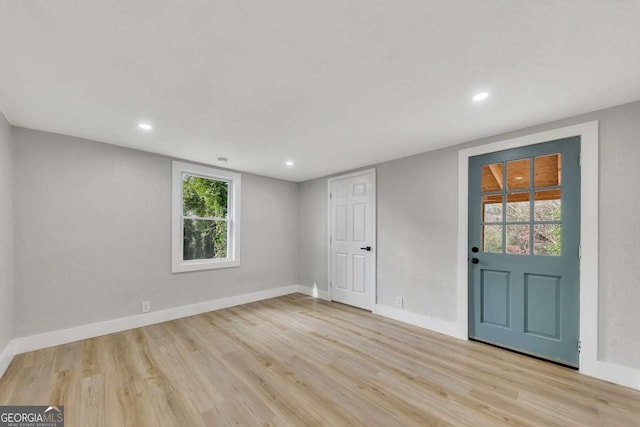 empty room with a wealth of natural light and light hardwood / wood-style flooring