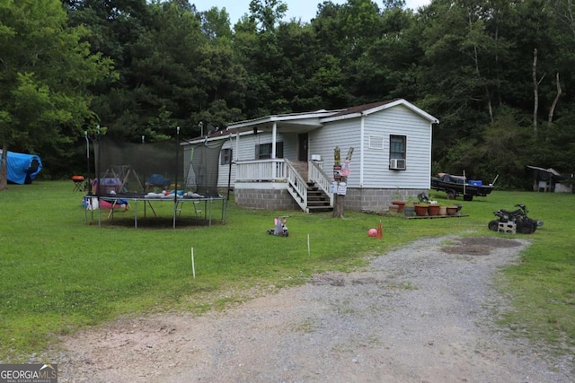 manufactured / mobile home featuring a front yard and a trampoline