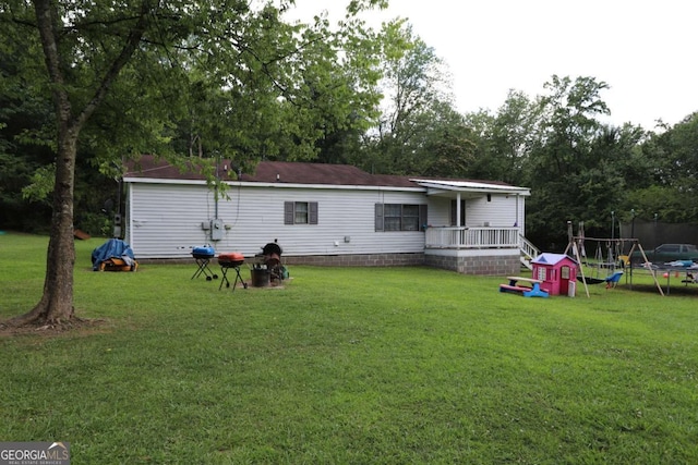 rear view of house with a lawn and a trampoline