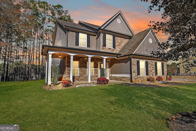 craftsman-style house featuring board and batten siding, stone siding, a porch, and a lawn