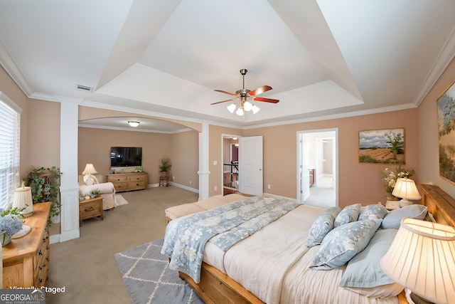 bedroom with a tray ceiling, light carpet, crown molding, and arched walkways