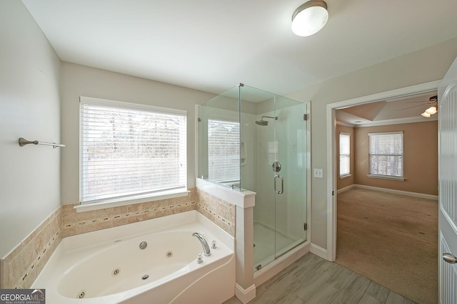 bathroom with a shower stall, a tub with jets, baseboards, and wood finished floors