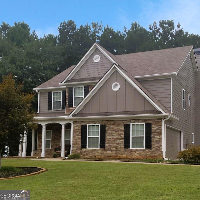 craftsman house with board and batten siding, a front yard, stone siding, and an attached garage