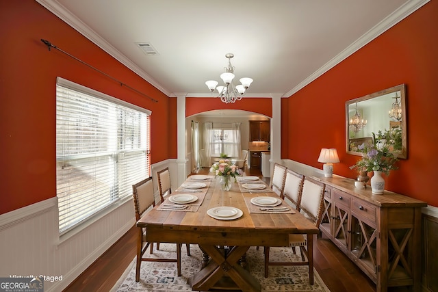 dining room with visible vents, arched walkways, wainscoting, wood finished floors, and a notable chandelier