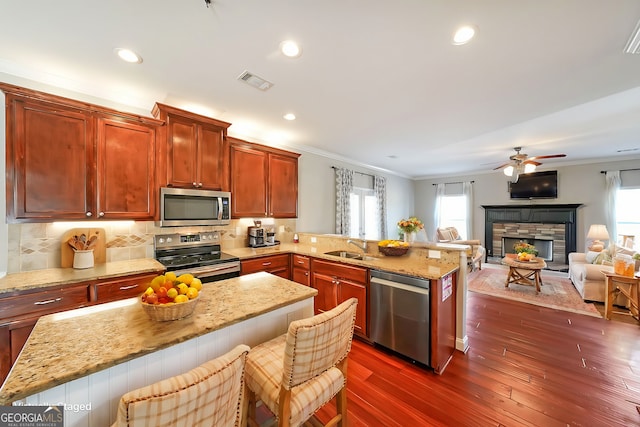 kitchen featuring stainless steel appliances, a peninsula, visible vents, open floor plan, and a kitchen bar