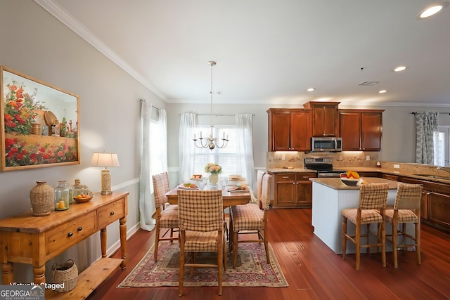 kitchen featuring dark wood finished floors, ornamental molding, decorative light fixtures, stainless steel appliances, and a notable chandelier