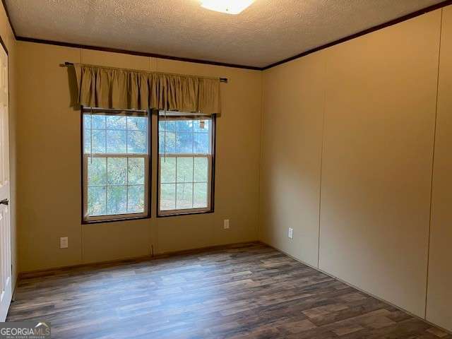 empty room featuring ornamental molding, a textured ceiling, and dark wood-type flooring