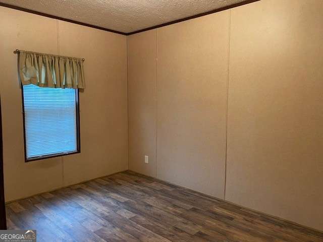 empty room with hardwood / wood-style flooring, crown molding, and a textured ceiling