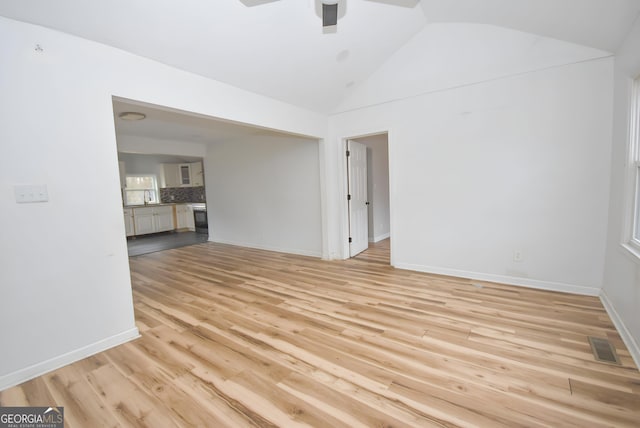 unfurnished living room with light wood-type flooring, ceiling fan, lofted ceiling, and sink