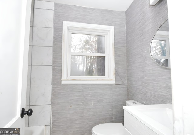 bathroom featuring vanity, toilet, and tile walls